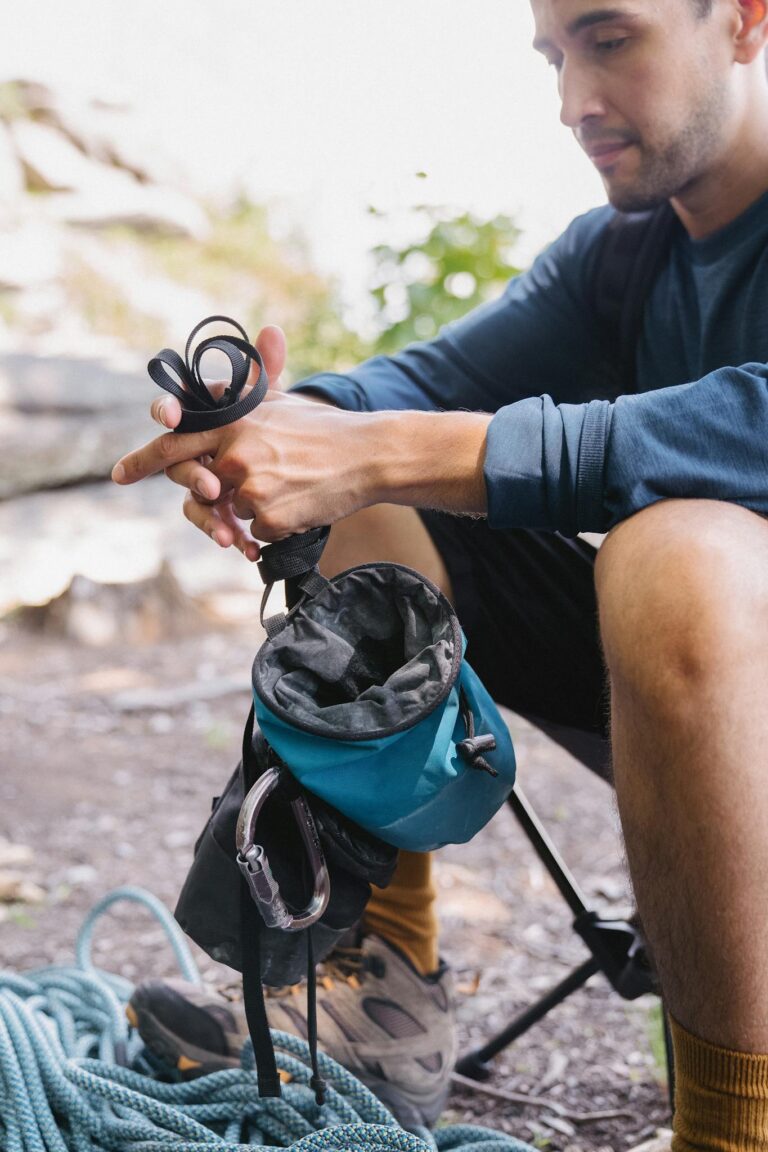 A hiker prepares climbing gear while resting outdoors, showcasing a blend of nature and adventure.