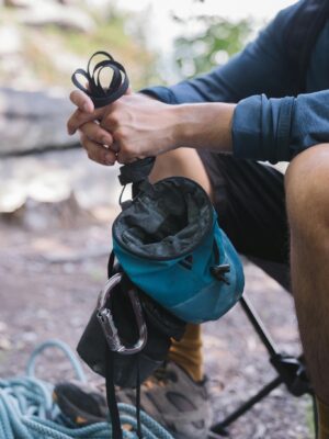 Climber holds chalk bag and rope outdoors, ready for a climbing adventure.
