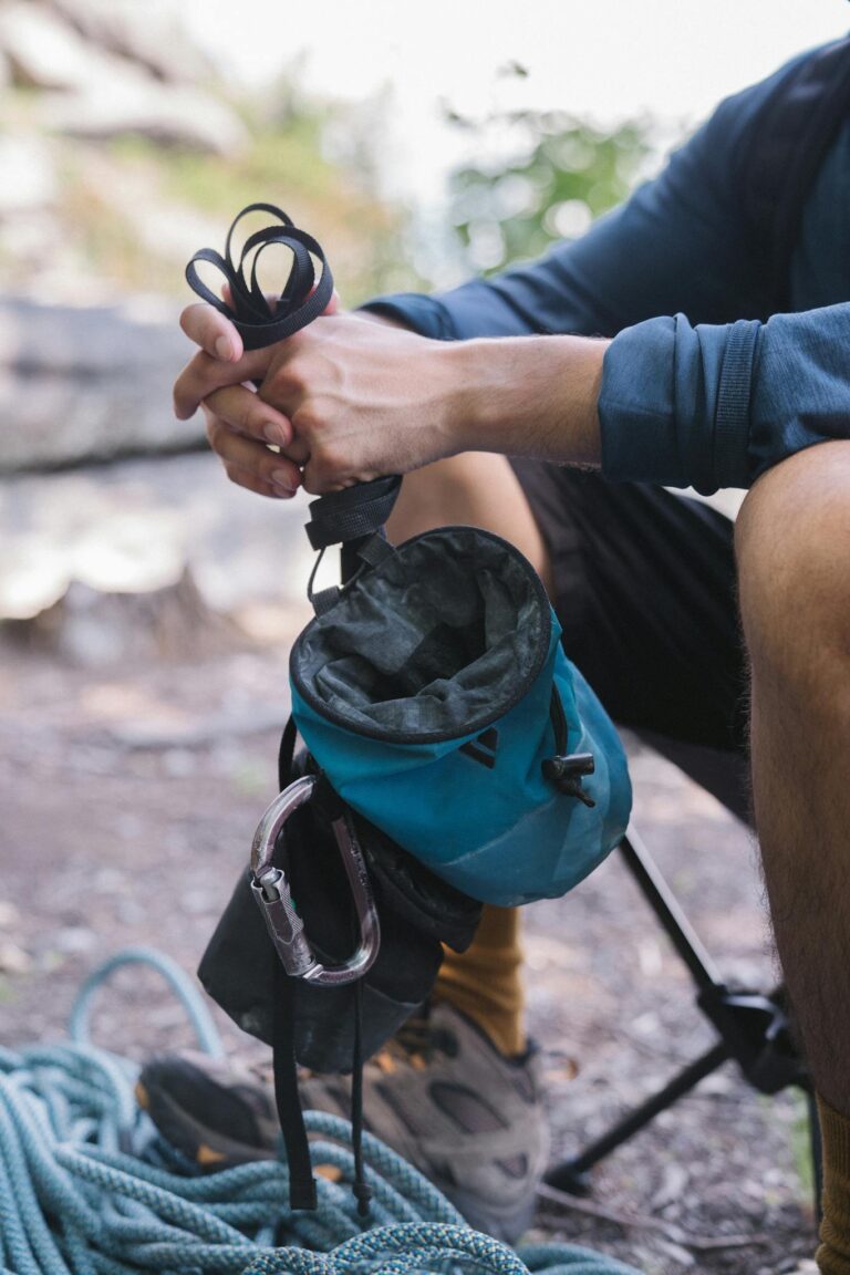 Climber holds chalk bag and rope outdoors, ready for a climbing adventure.